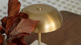 Soft cloth cleaning a brass-finish lamp beside a linen shade and marble base
