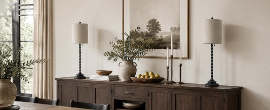 Two Lampworks black spindle buffet lamps with linen shades on a wooden sideboard in a farmhouse-style dining room.