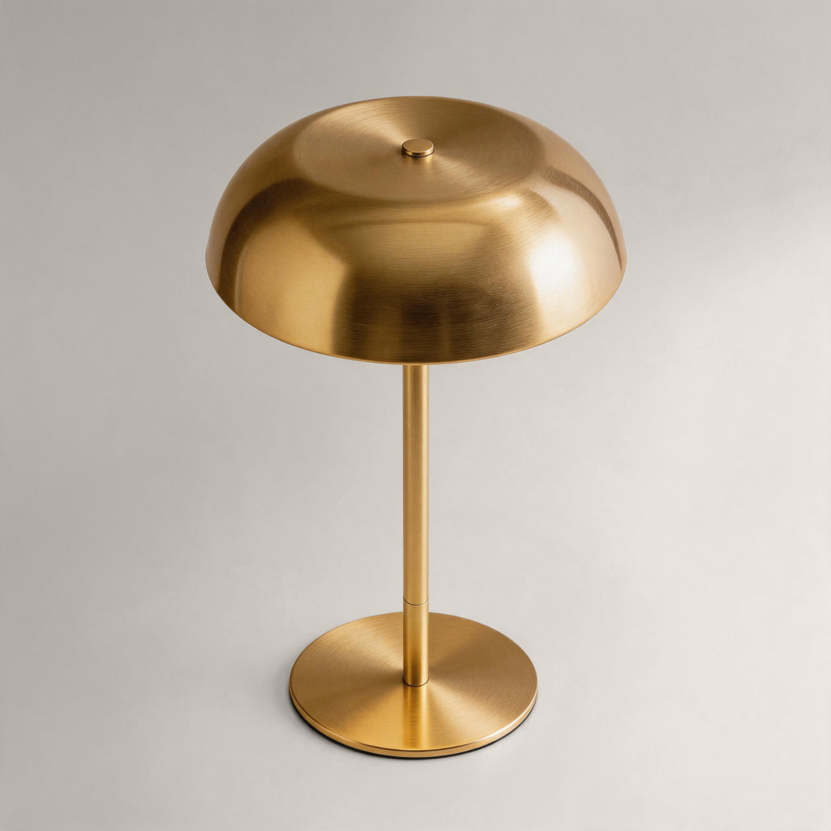 Brushed brass cordless mushroom table lamp shown from an elevated angle