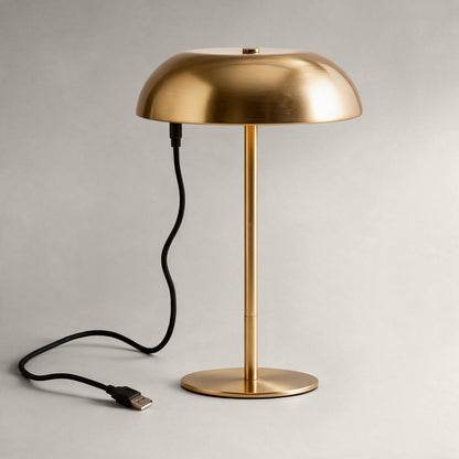 Brushed brass cordless mushroom table lamp connected to a USB charging cable