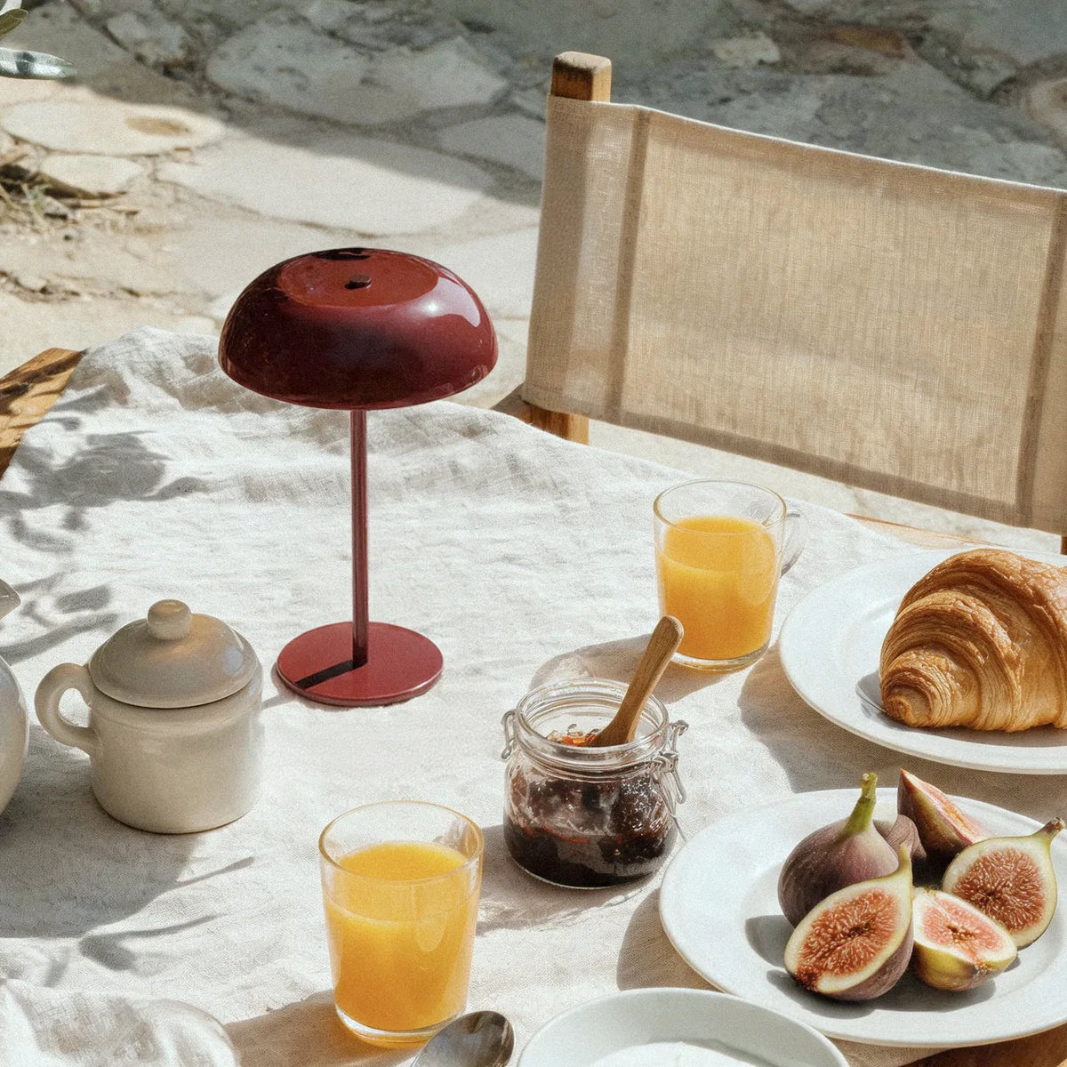 Oxblood red cordless mushroom table lamp at an outdoor breakfast