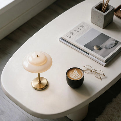 Lampworks opal glass table lamp on a white coffee table beside a latte, eyeglasses and books