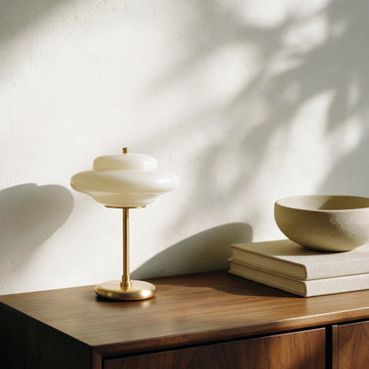 Unlit Lampworks glass table lamp with a milky white shade on a sunlit wood sideboard