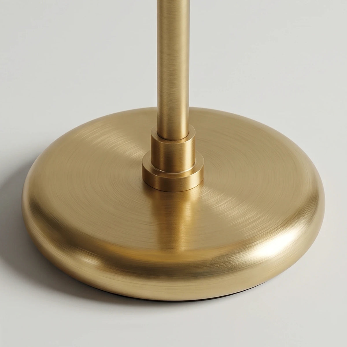 Close-up of the Lampworks glass table lamp's round brass-tone base and slender stem