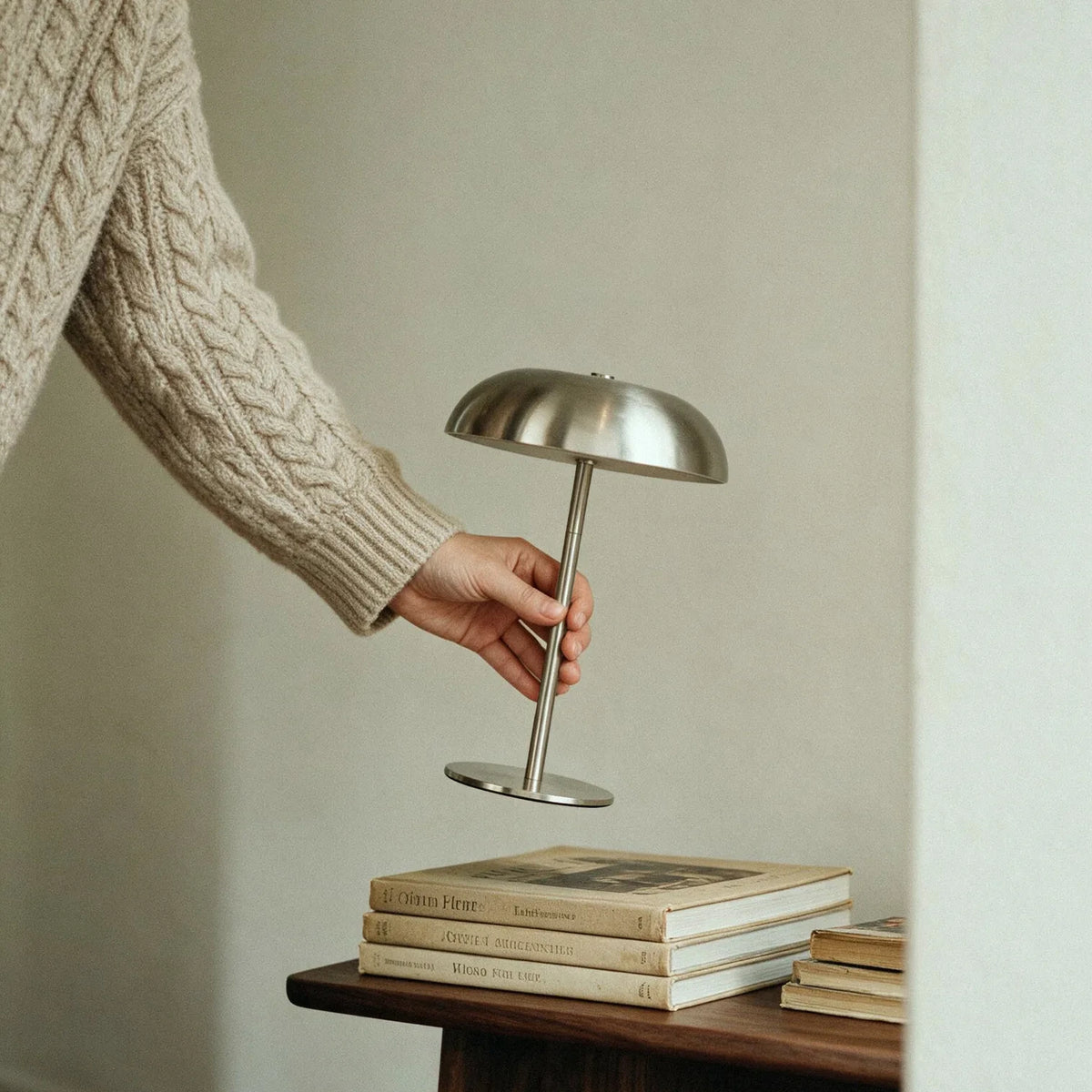 Hand holding a portable silver cordless mushroom table lamp
